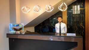 Un mostrador de recepción con un letrero que dice "RECEPTION!" y un cartel de prohibido fumar encima.