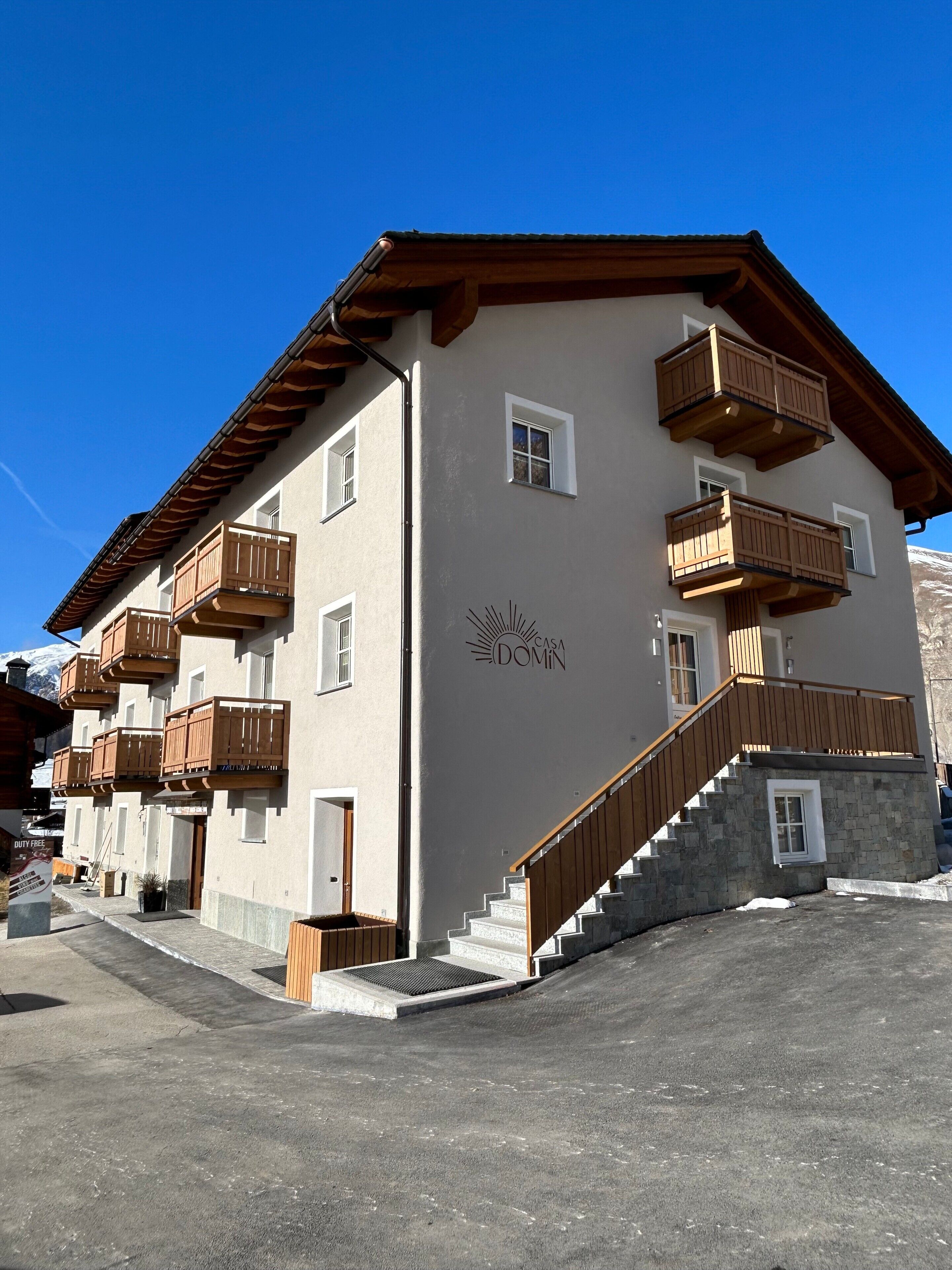 A multi-story building with wooden balconies, a stone staircase, and a sign reading 'CASA DOMIN.'