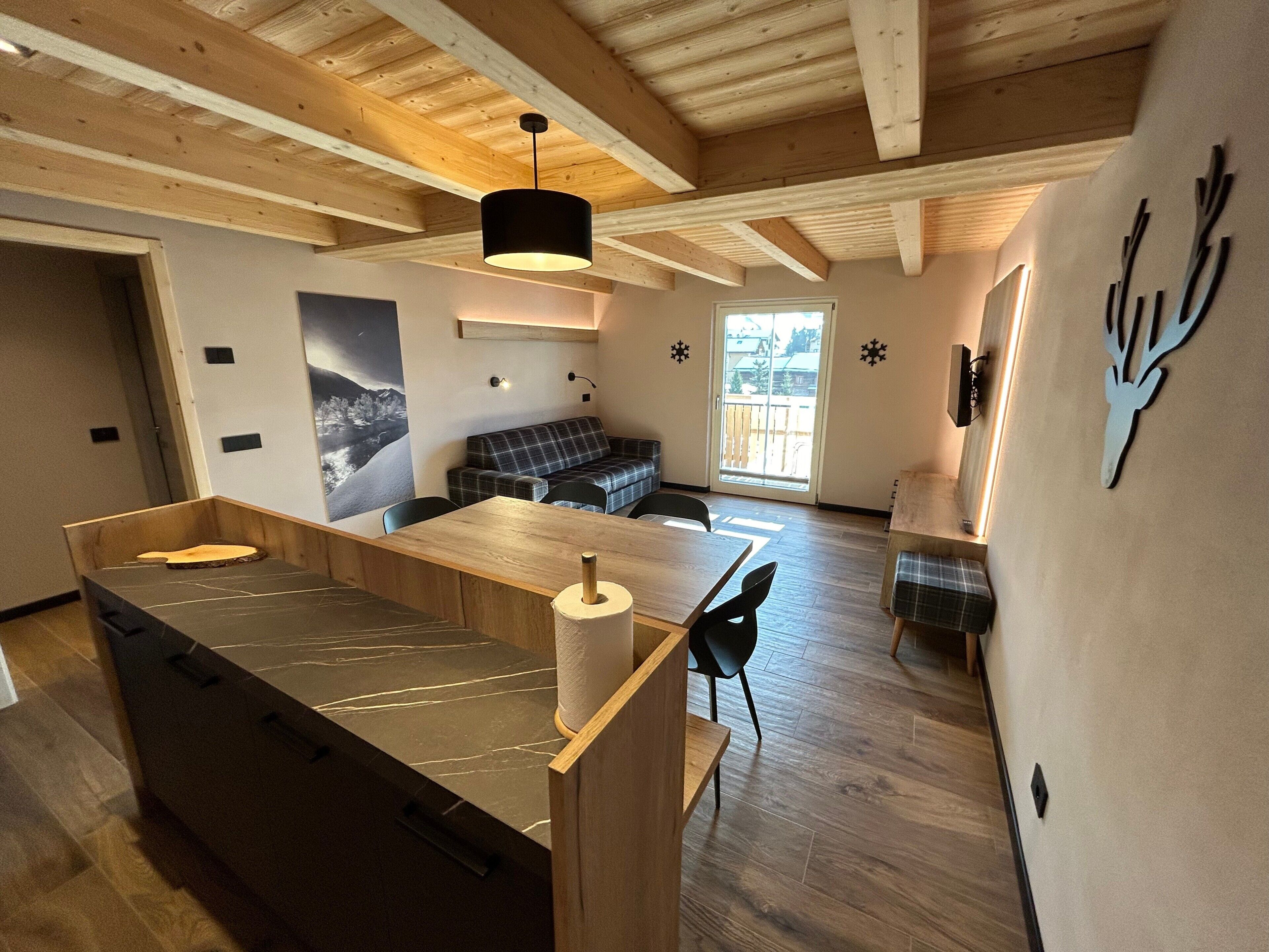 A modern interior with a wooden dining area, a sofa, and a wall-mounted deer head decoration.