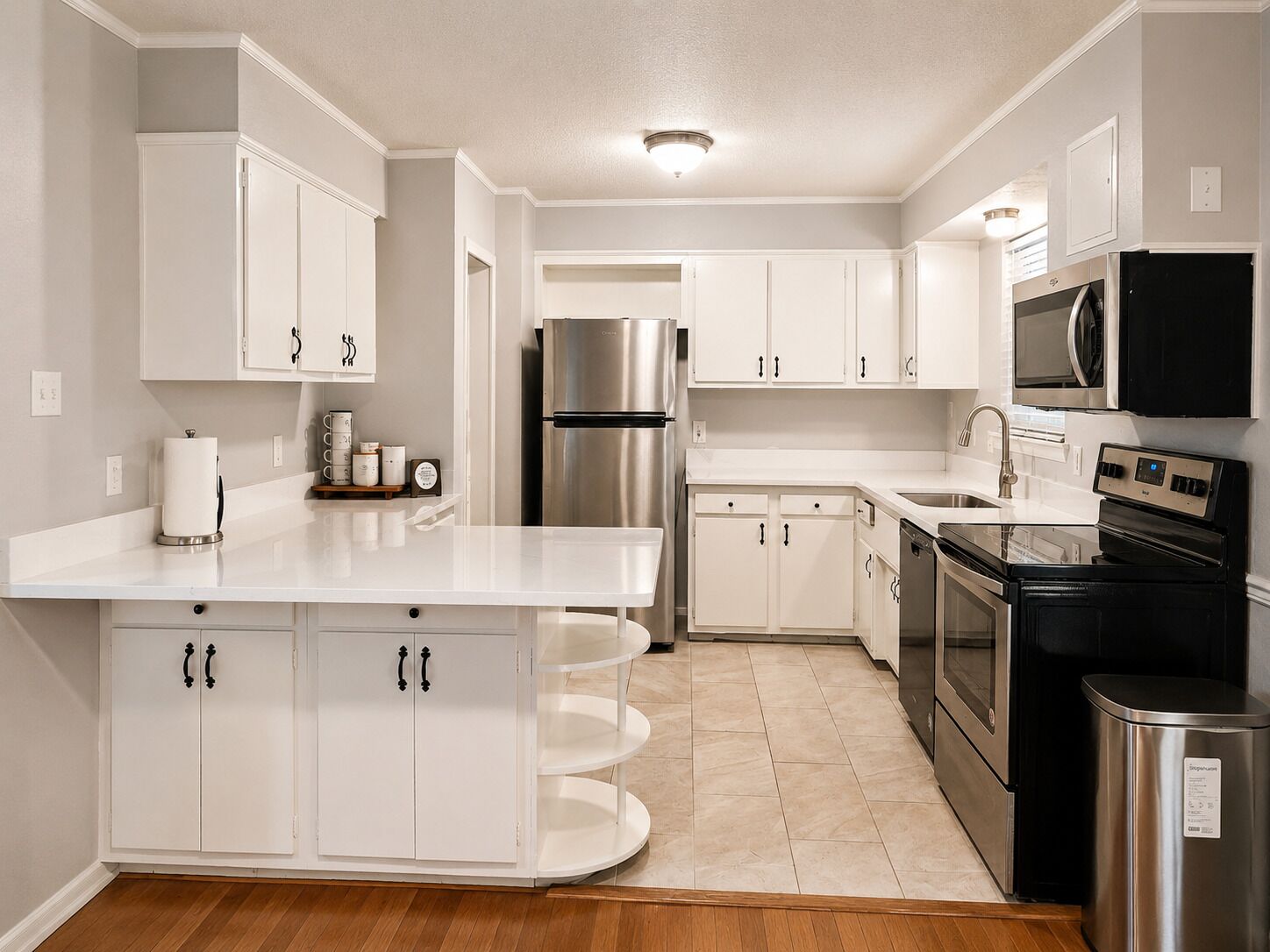 Una cocina moderna con armarios blancos, electrodomésticos de acero inoxidable y una isla central.