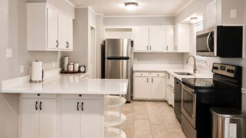 A modern kitchen with white cabinetry, stainless steel appliances, and a central island.