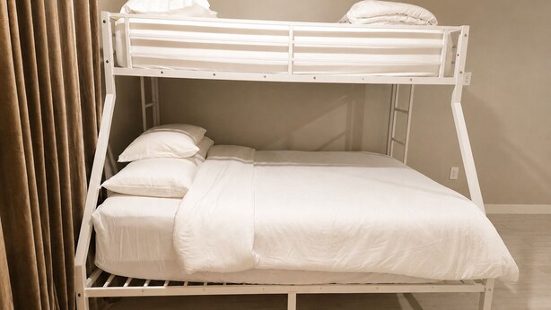 Una cama litera con ropa de cama blanca, estructura de madera y una cortina entreabierta.