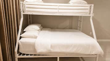 A bunk bed with white bedding, a wooden frame, and a curtain partially drawn to the side.
