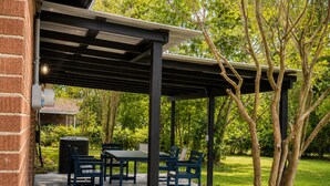Un patio exterior con pérgola, una mesa y sillas.