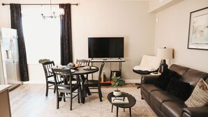 Una sala de estar moderna con comedor, televisor de pantalla plana, sofá y mesa de centro.