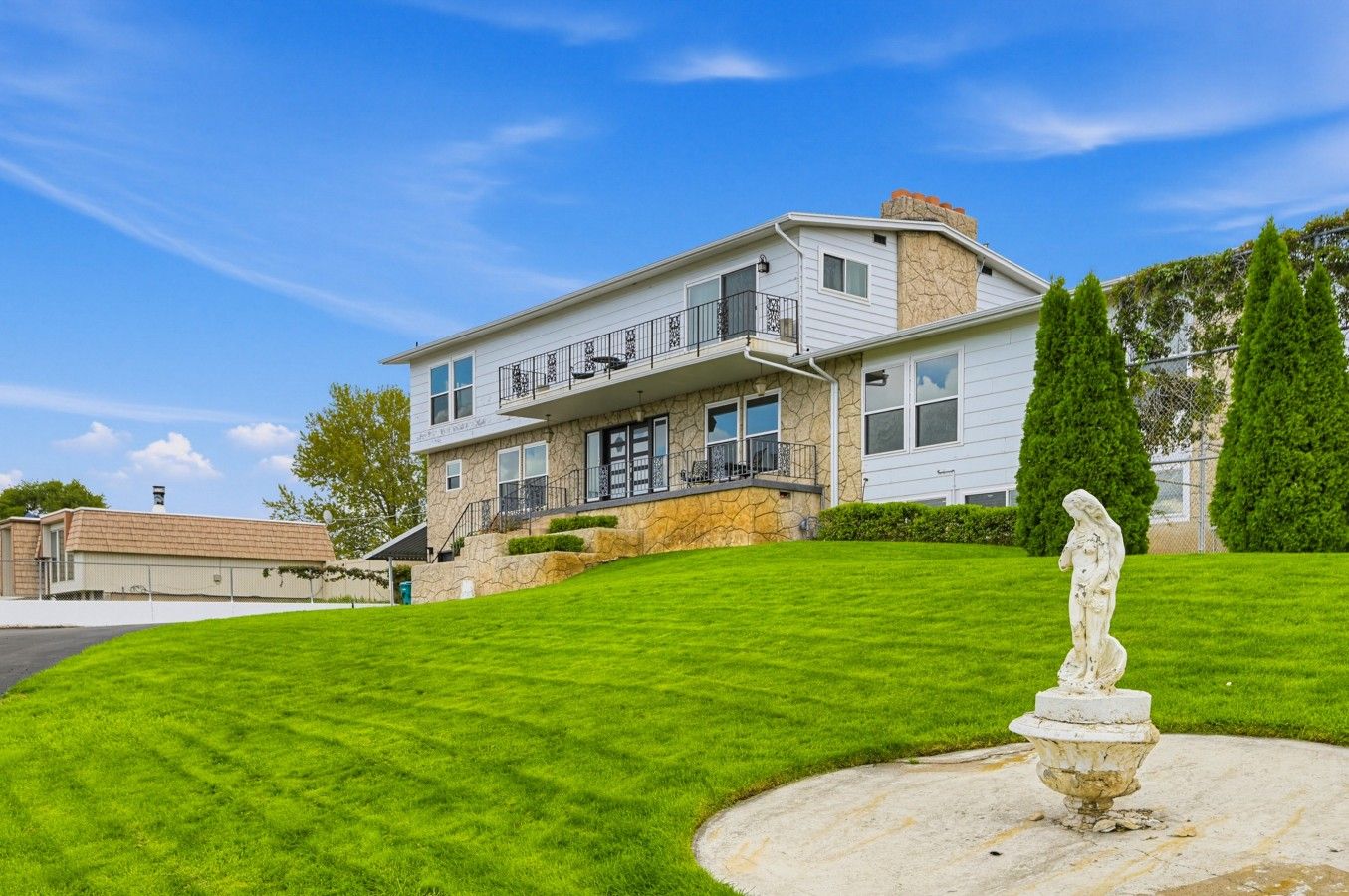 A two-story house with a stone facade, a front porch, and a well-maintained lawn.