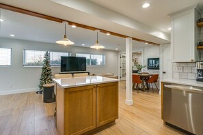 Una cocina moderna con una isla central, armarios de madera e iluminación colgante.