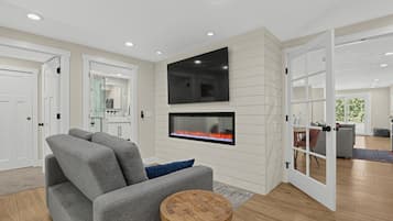 A modern living room with a fireplace, a flat-screen TV, and a grey sofa.