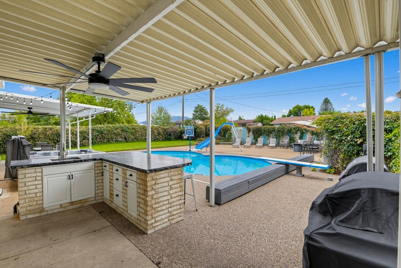 A covered outdoor area with a pool, a barbecue grill, and a seating area.
