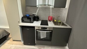 A compact kitchenette with a built-in oven, a stovetop, a sink, and a compact dishwasher. - Central London, Zone 2, Studio Flat (Greater London)