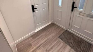A hallway with wooden flooring, white walls, and two doors with black handles. - Central London, Zone 2, Studio Flat (Greater London)
