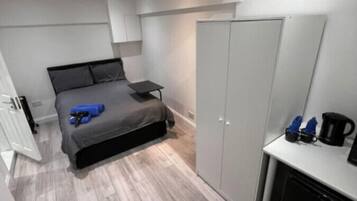 A compact bedroom with a bed, a small table, and a wardrobe.