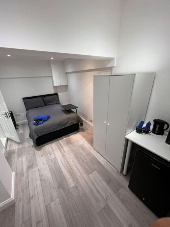 A compact bedroom with a bed, a small table, and a wardrobe.