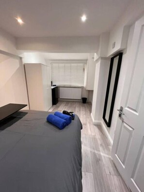 A modern bedroom with a bed, a desk, and a radiator.
