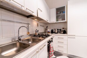 A modern kitchen with stainless steel appliances, white cabinetry, and a tiled backsplash. - Casa Cleo Your Cozy and Charming Nest in Arezzo (Arezzo)
