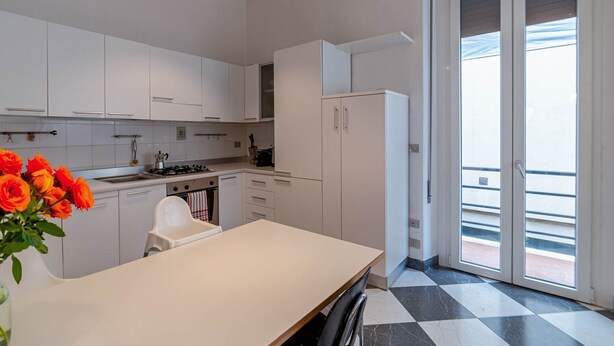 Een moderne keuken met witte kasten, een eettafel en uitzicht op buiten via een schuifdeur.