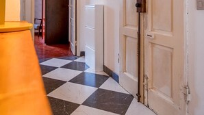 Een gang met een zwart-wit geruit vloerkleed, een lamp en twee deuren.