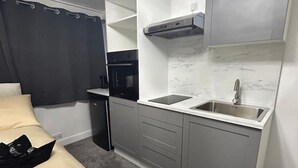 A compact hotel room with a kitchenette, a bed, and a small bathroom. - Central London Studio zone 1 (Greater London)