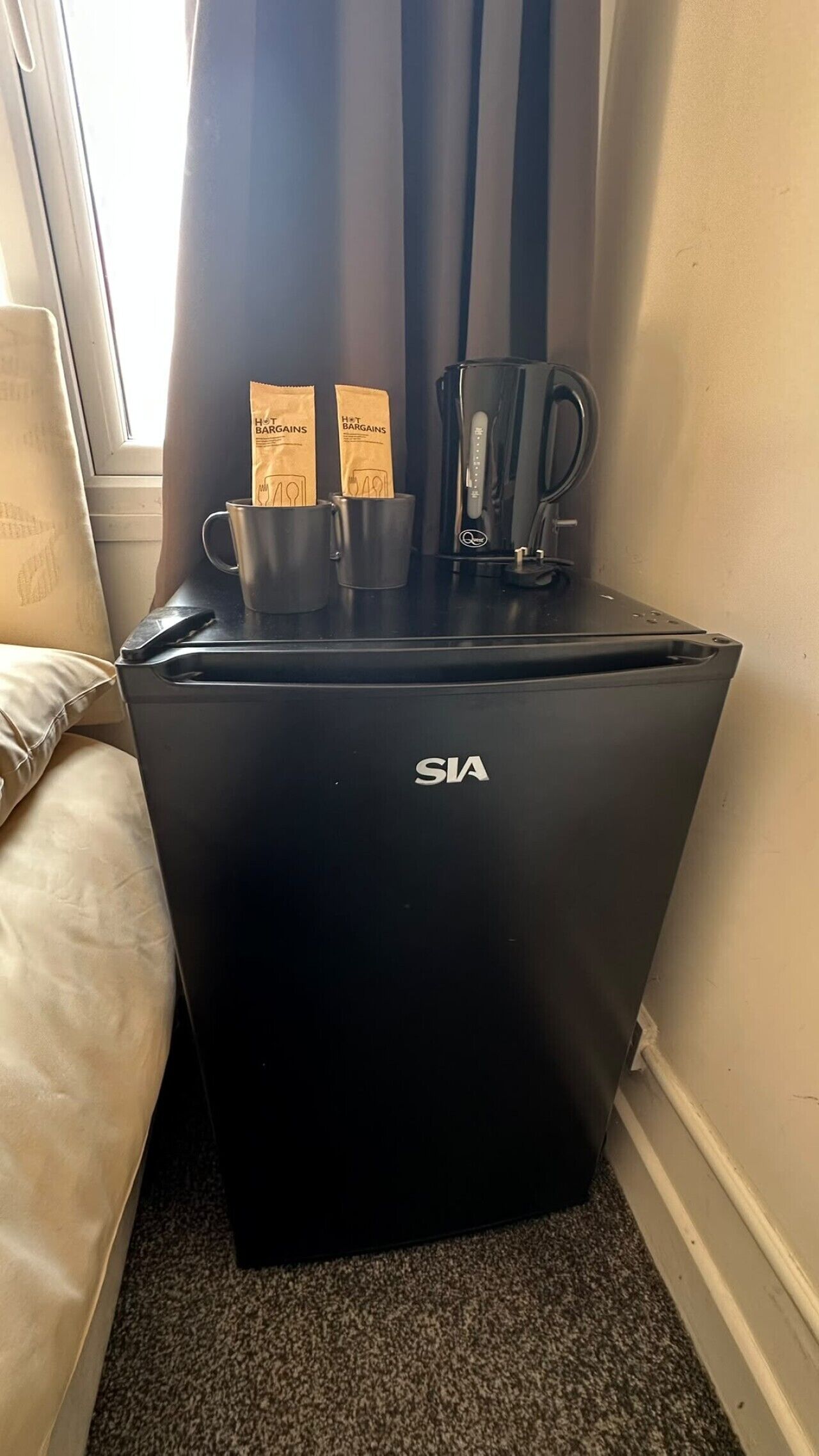A black minibar with two hot bar bargains packets, a coffee maker, and a water dispenser.