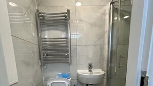 Un baño moderno con inodoro, bidé, lavamanos y cabina de ducha de vidrio.