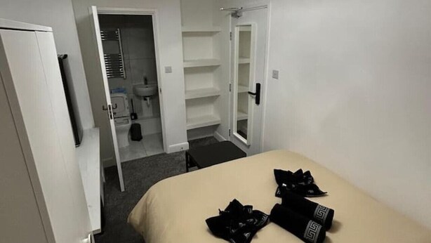 Une chambre d’hôtel avec un lit, une armoire et une salle de bain, visibles à travers une porte ouverte.