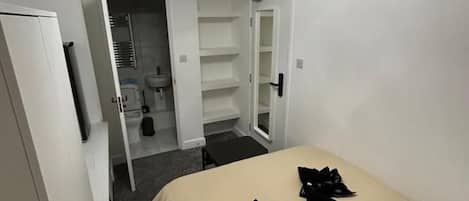 A hotel room with a bed, a closet, and a bathroom visible through an open door.