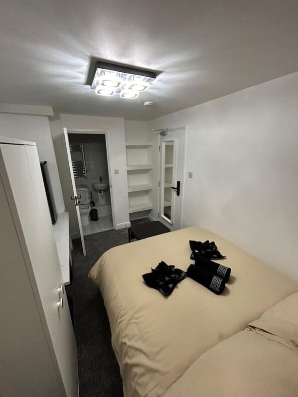 A hotel room with a bed, a closet, and a bathroom visible through an open door. - Marylebone Room + bathroom (Greater London)