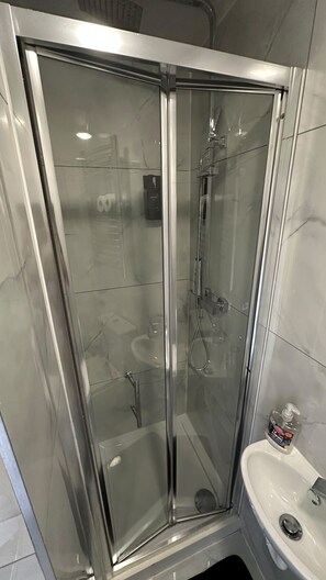 A glass-enclosed shower stall with a handheld showerhead and a handheld shower attachment. - Baker Street room moments away (Greater London)