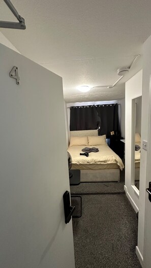 A narrow hallway leading to a bedroom with a bed, a bedside table, and a ceiling fan. - Baker Street room moments away (Greater London)
