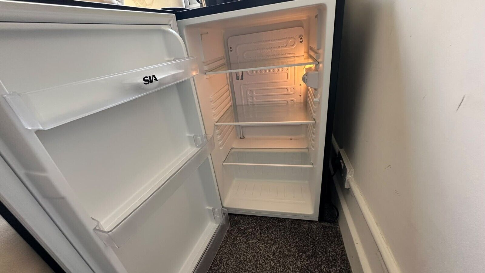 An interior of a refrigerator with multiple shelves and a freezer compartment.