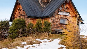 A wooden church with a bell tower and a cross, surrounded by natural landscape. - Arrive.feel good.enjoy (Wagrain)