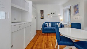 Een moderne keuken met witte kasten, een blauwe bank en een ronde eettafel.