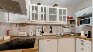 Een moderne keuken met witte kastjes, een zwarte inductiekookplaat, een magnetron en een broodrooster.