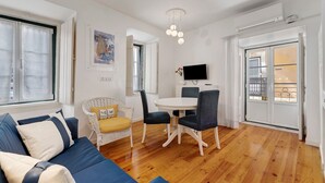 Een moderne woonkamer met een bank, stoelen, een eettafel en een televisie.