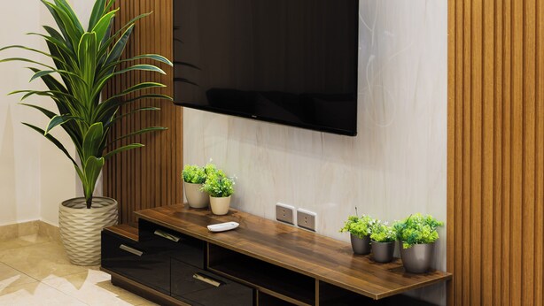Un salon moderne avec un téléviseur à écran plat fixé à un mur en bois, un meuble de rangement en bois en dessous et une plante en pot sur le côté gauche.