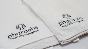Des serviettes blanches, pliées avec soin, ornées du logo et de l’inscription « Pharaohs Hospitality Management ».