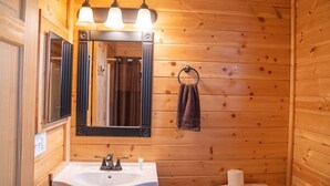 Un baño rústico con cabaña, que incluye un lavabo, espejo y retrete.