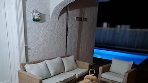 Ein gemütlicher Außenbereich mit Korbmöbeln und einem kleinen dekorativen Gegenstand an der Wand.