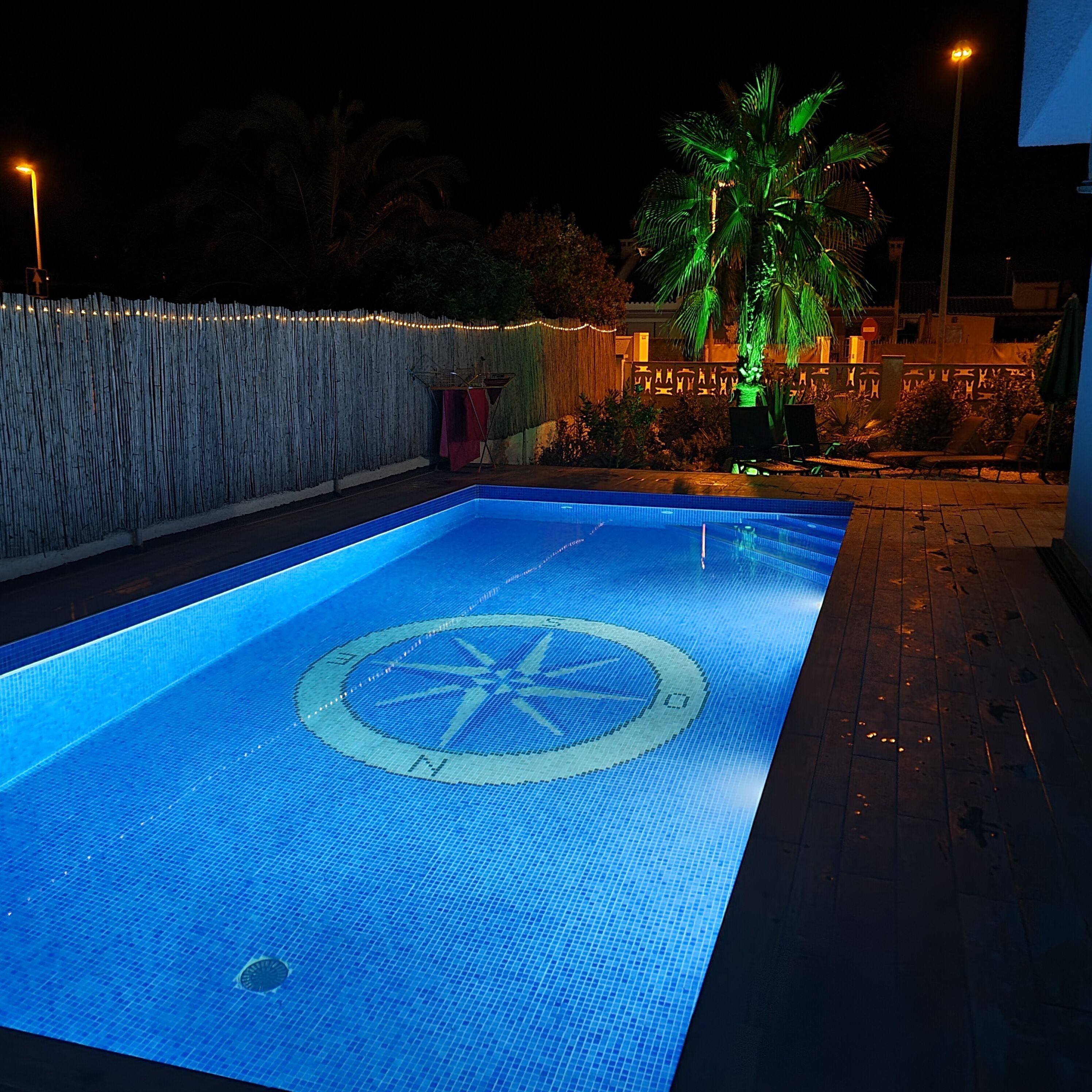 A swimming pool with a blue tiled floor and a central circular design.