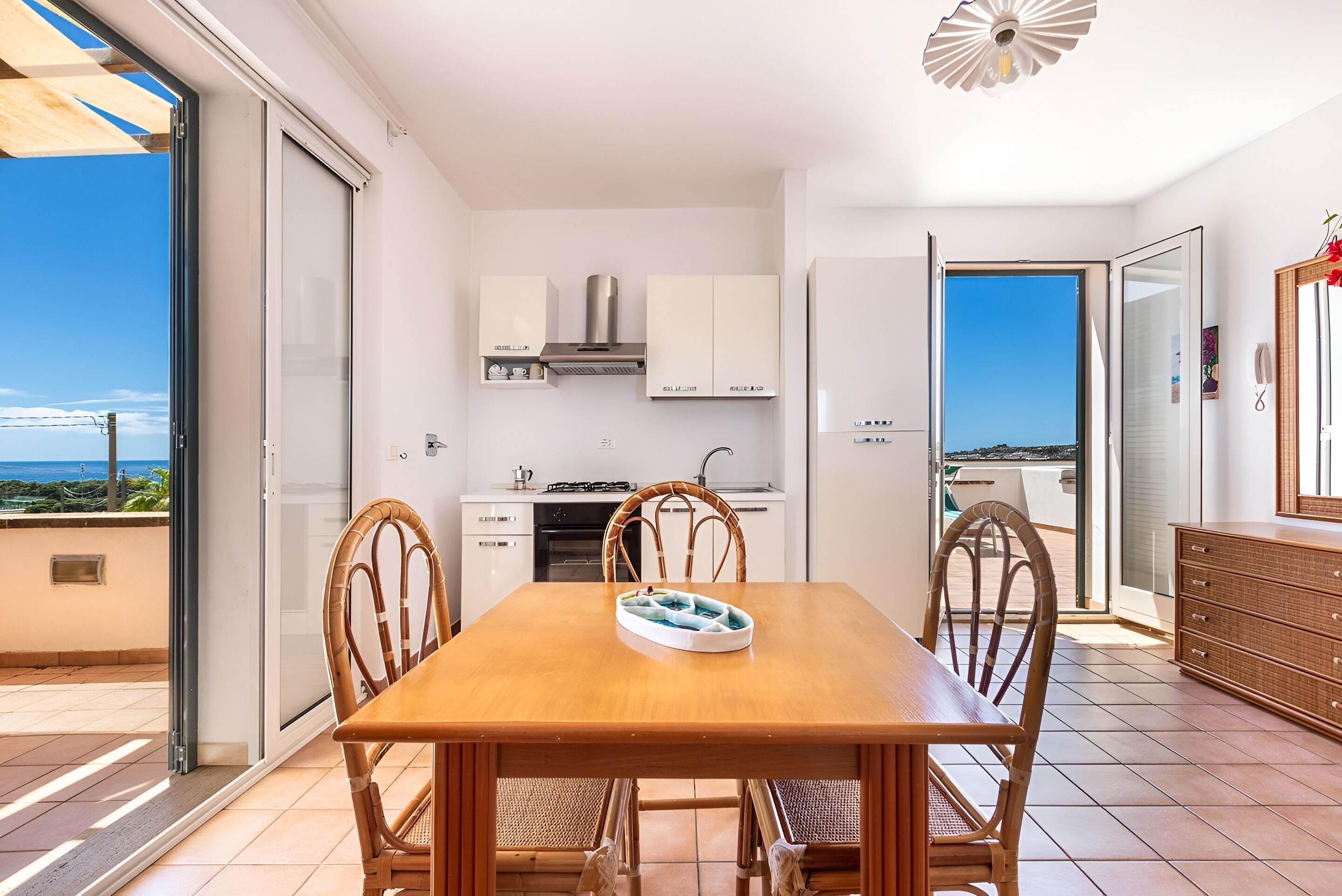 Une cuisine moderne avec des meubles blancs, une cuisinière et une vue sur la mer.