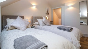Camera da letto con due letti, un lucernario, uno specchio e una porta che dà su un'altra stanza.