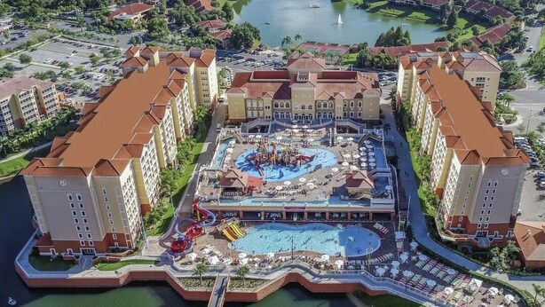 Een resort met meerdere gebouwen, een centraal zwembadgedeelte met glijbanen en een jachthaven op de achtergrond.