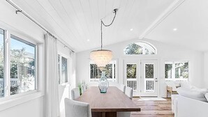A spacious dining area with a wooden table and chairs, large windows, and a view of the outdoors. - Coastal Calm (Santa Rosa Beach)