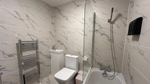 Ein Badezimmer mit Badewanne, Toilette und Dusche.