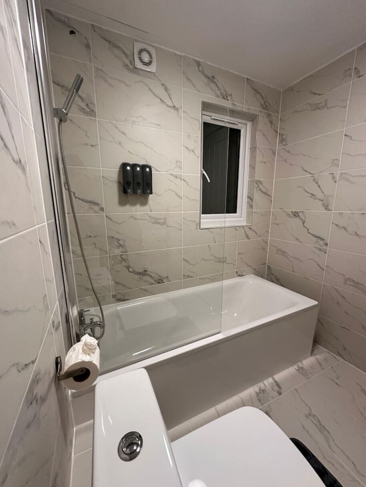 A bathroom with a glass-enclosed shower, a bathtub, and a toilet.