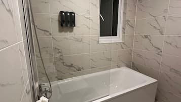 A bathroom with a glass-enclosed shower, a bathtub, and a toilet.