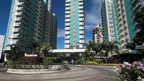 A modern residential complex with high-rise buildings, a landscaped entrance area, and a clear sky. - Your Home Away From Home | Journey & Rest Staycation (Bacolod)
