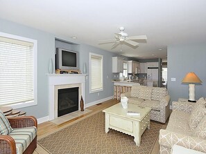A living room with a fireplace, a television, and a ceiling fan. - Oceanfront 3BR Condo in Fenwick | Walk to Beach! (Fenwick Island)