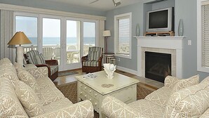 A living room with patterned sofas, a fireplace, a television, and a ceiling fan. - Oceanfront 3BR Condo in Fenwick | Walk to Beach! (Fenwick Island)
