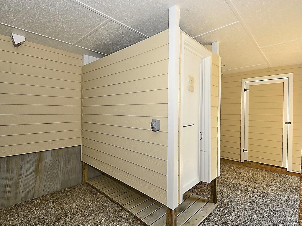 A room with a wooden floor, a white door, and a beige wall.